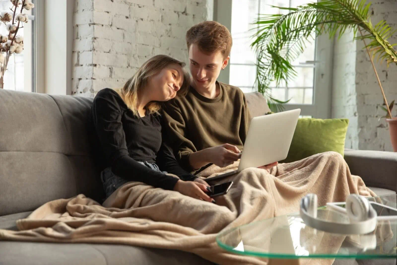 Kobieta i mężczyzna siedzą wygodnie na kanapie, przeglądając strony zawierające oferty typu pożyczka dla każdego.