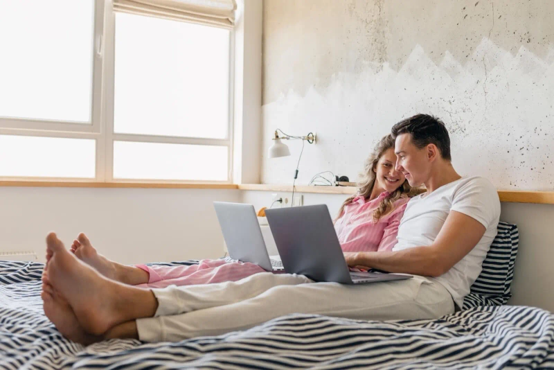 Mężczyzna i kobieta siedzą na łóżku i przeglądają pożyczki online bez weryfikacji konta