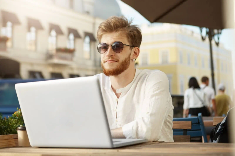 Mężczyzna siedzący z laptopem w kawiarni, szukający chwilówki bez przelewu grosza